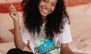 A young woman smiling and having fun with a palate of makeup.