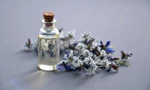 A bottle of fragrance and some flowers on a table.