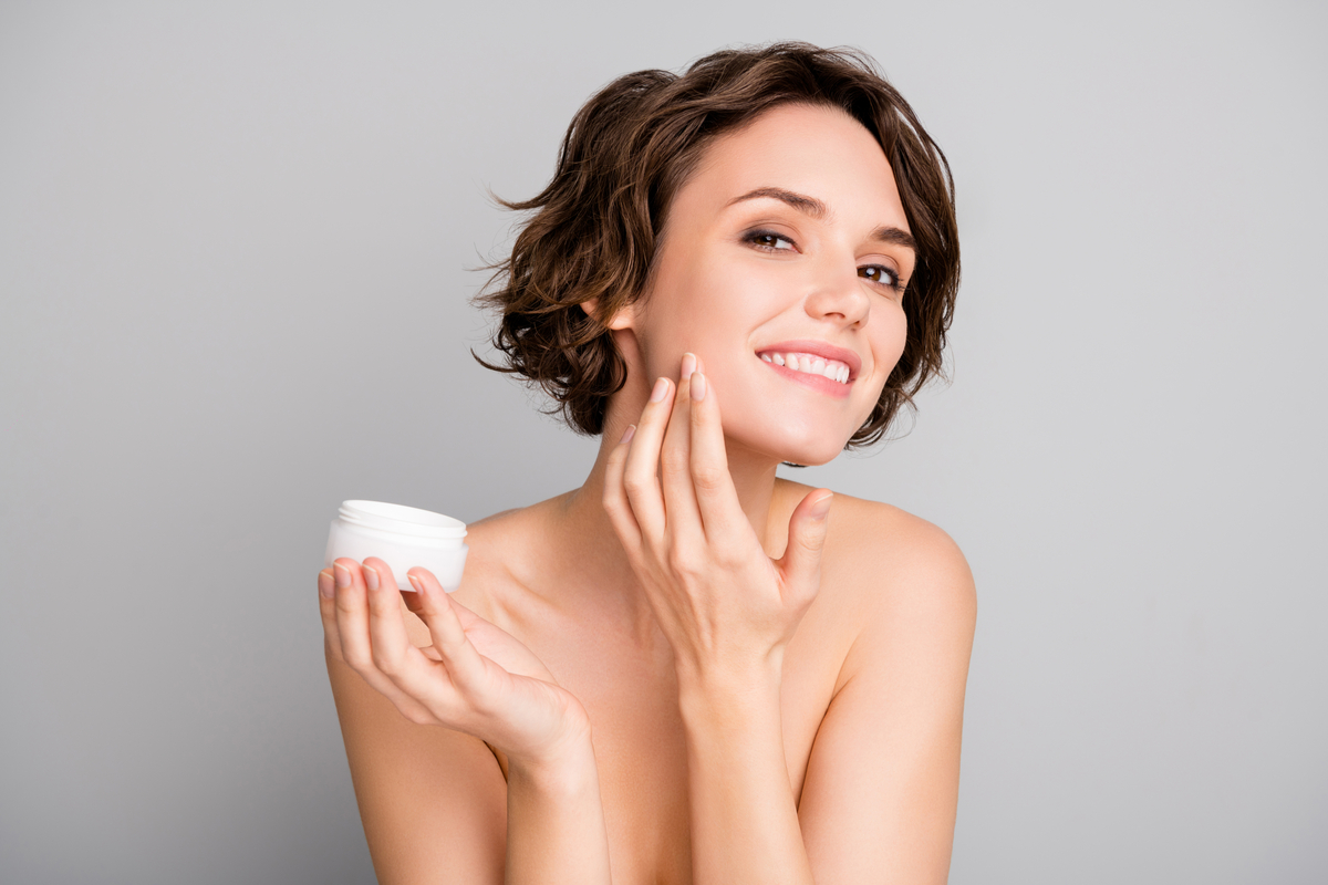 A woman applying a cream to her face.