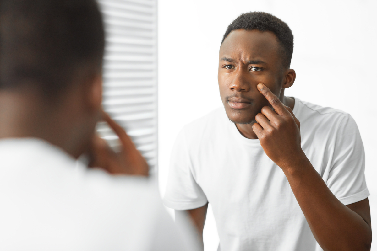 A man looking at his face in a mirror.