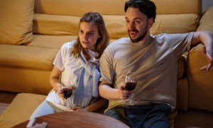 Man and woman watching tv with wine