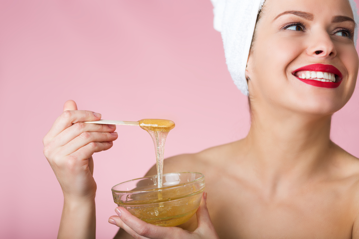 A woman holding a bowl of sugar paste for hair removal.