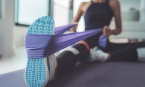 A woman stretches her leg with a resistance band